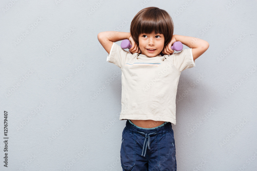 Happy cute little boy doing exercises with dumbbells Happy cute little boy doing exercises with dumbbells