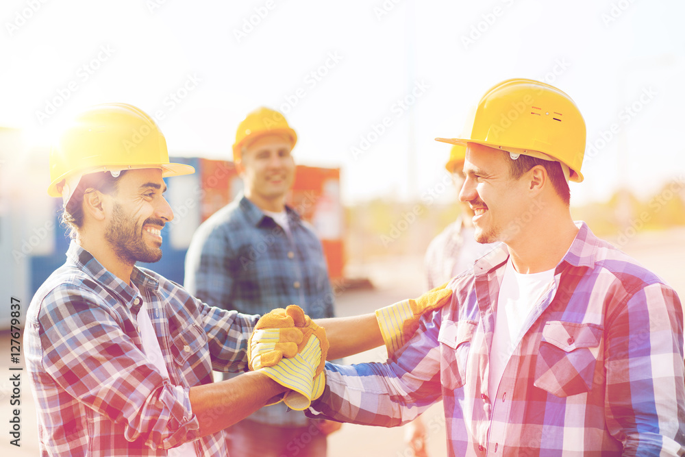 group of smiling builders in hardhats outdoors group of smiling builders in hardhats outdoors