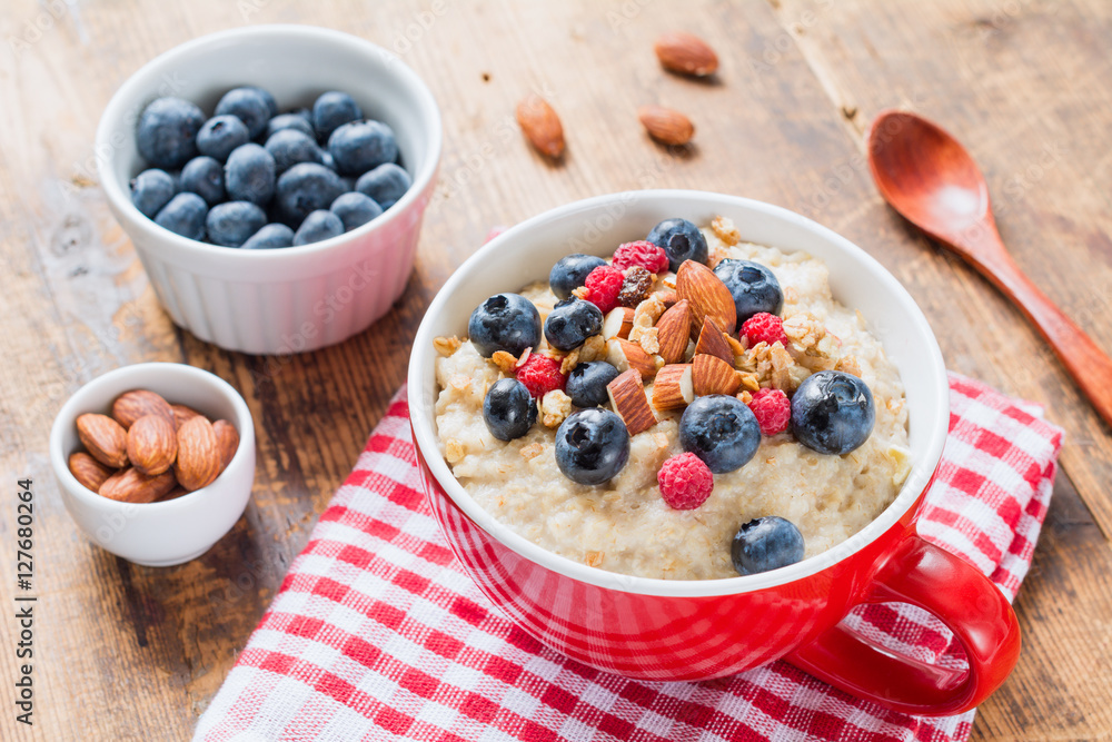Porridge bowl, oats porridge with blueberries and almonds in red bowl Porridge bowl, oats porridge with blueberries and almonds in red bowl