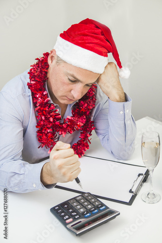 Feeling sick and tired. Frustrated young man keeping eyes closed. Business Man Celebrate Merry Christmas And Happy New Year Wear Santa hat photo