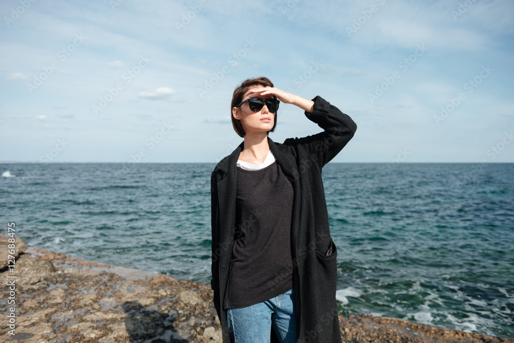 Pretty young woman standing and looking far away on seaside Pretty young woman standing and looking far away on seaside