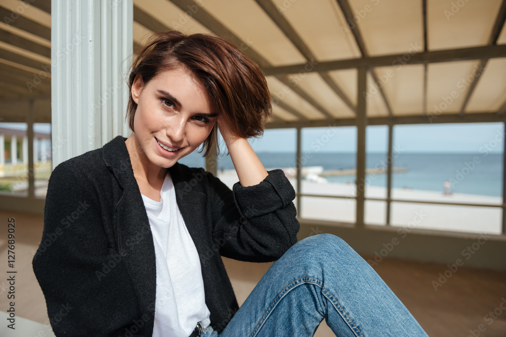 Happy attractive young woman sitting on terrace near the sea Happy attractive young woman sitting on terrace near the sea
