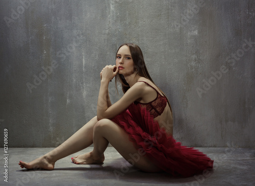 Portrait of slim young girl dancer in red tutu is sitting on a b © Aleksey Sergeychik