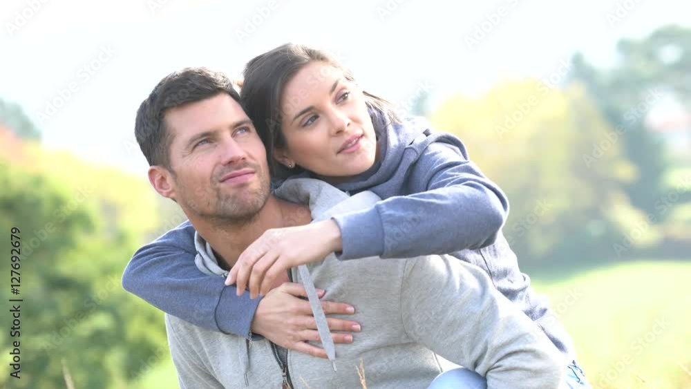 Man giving piggyback ride to girlfriend in countryside Man giving piggyback ride to girlfriend in countryside