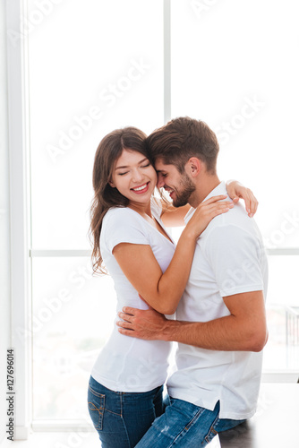 Tender couple smiling and hugging at home