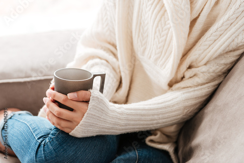 Woman with cup of coffee sitting on sofa at home