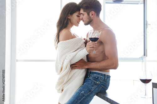Beautiful sensual young couple embracing and drinking red wine
