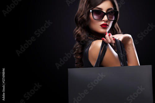 Shopping woman holding grey bag isolated on dark background in black friday holiday