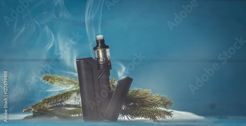 vaporizer with a black box on a blue background with fir branches photo