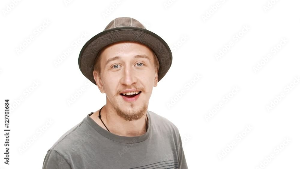 Surprised young handsome man in hat smiling, laughing over white background. Slow motion. Surprised young handsome man in hat smiling, laughing over white background. Slow motion.