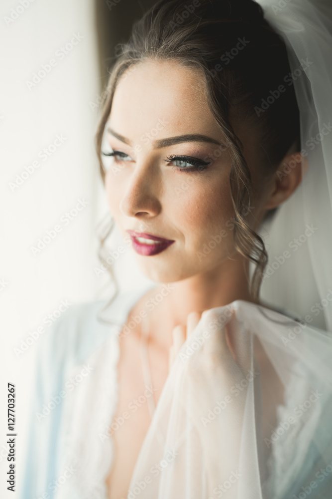 Beautiful young bride with makeup and hairstyle in bedroom, newlywed woman final preparation for wedding. Happy girl waiting groom. Portrait soft focus Beautiful young bride with makeup and hairstyle in bedroom, newlywed woman final preparation for wedding. Happy girl waiting groom. Portrait soft focus
