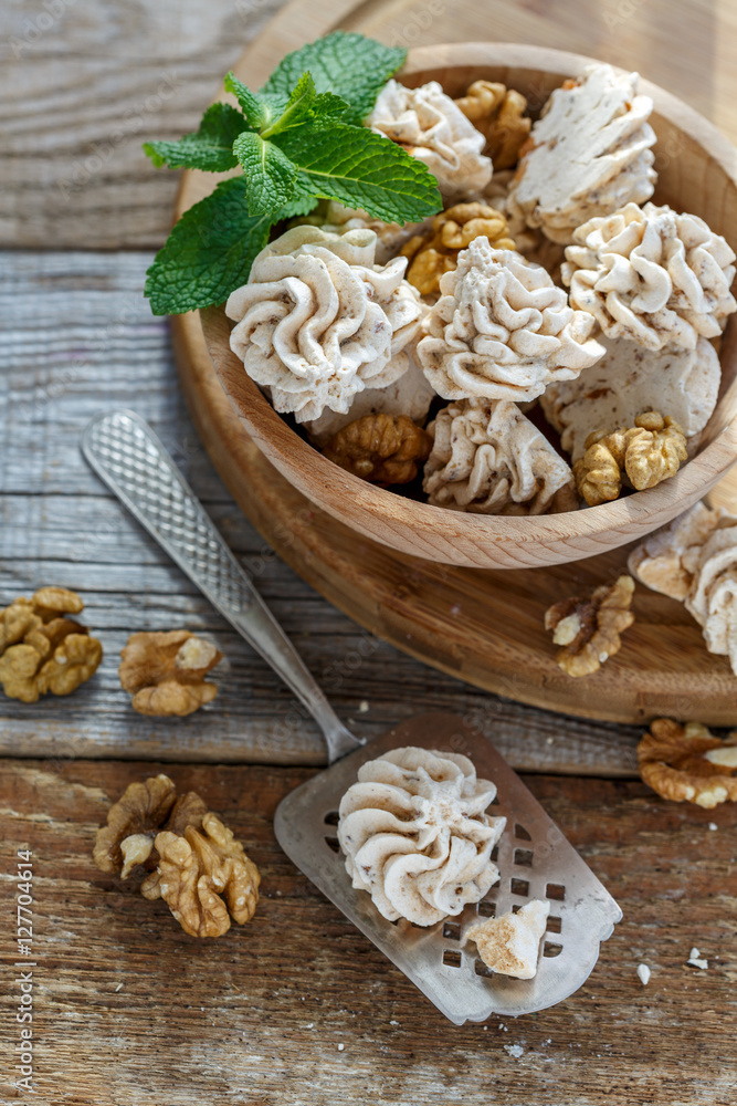 Meringue cakes with walnuts in a wooden bowl.