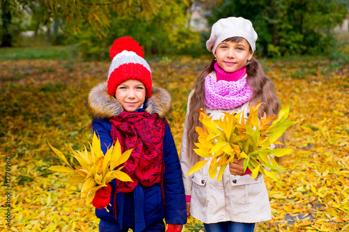 two little girls in autumn park with leafs