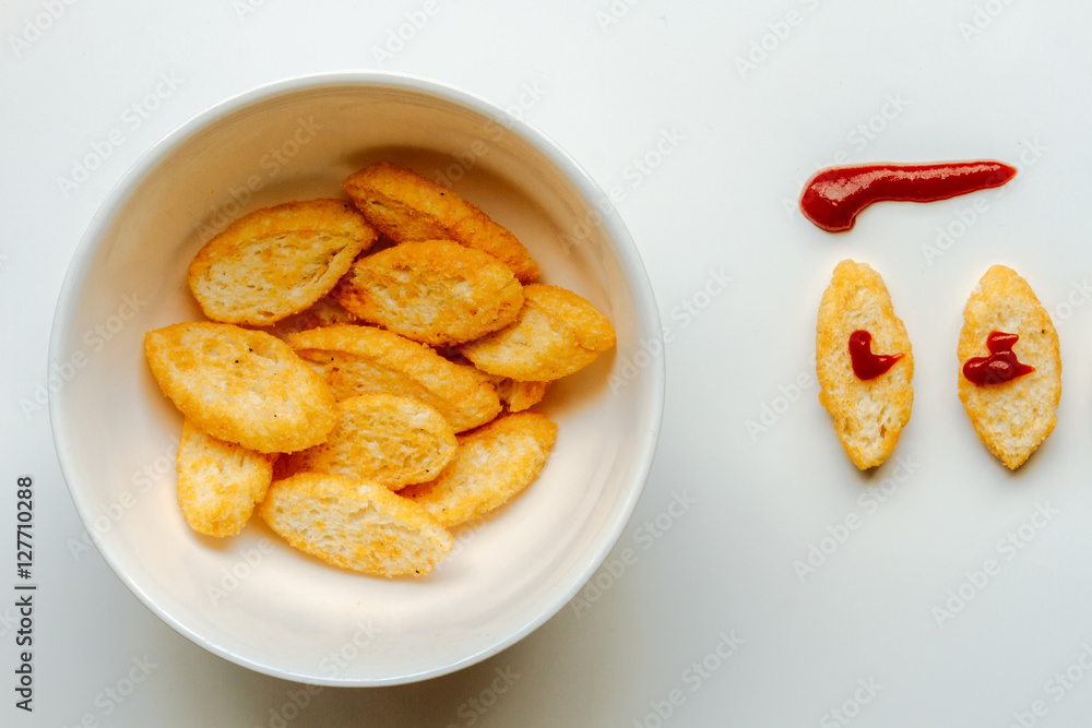 Toasts next to white bowl full of toast with olive oil and ketch