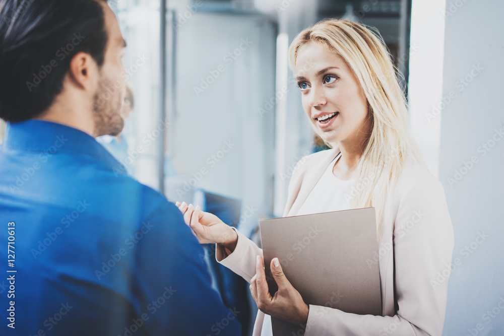 Fototapeta premium Two coworkers discussing business project in modern office.Successful confident hispanic businessman talking with woman. Horizontal, blurred background.