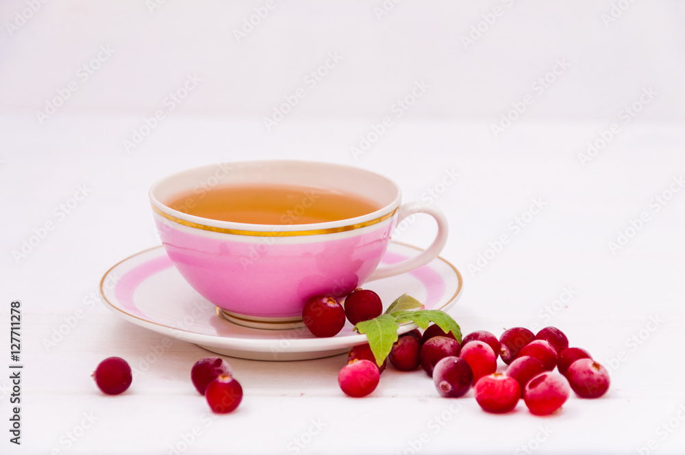 Pink cup of tea and cranberries on white background Pink cup of tea and cranberries on white background