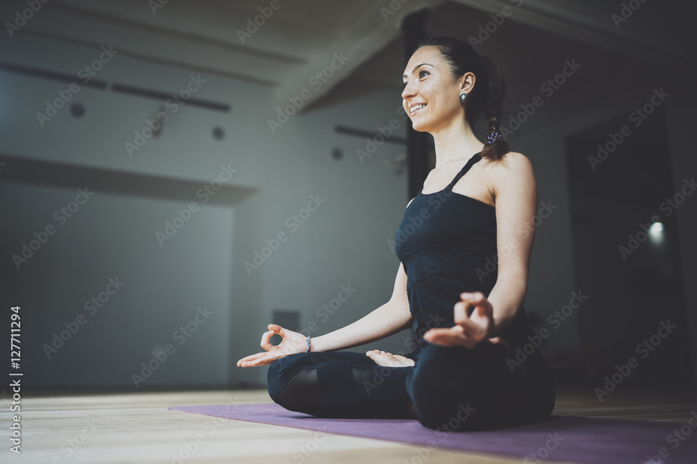 Portrait of happy young woman practicing yoga indoor. Beautiful girl practice lotus position in class.Calmness and relax, female happiness.Horizontal, blurred background, flares. Portrait of happy young woman practicing yoga indoor. Beautiful girl practice lotus position in class.Calmness and relax, female happiness.Horizontal, blurred background, flares.