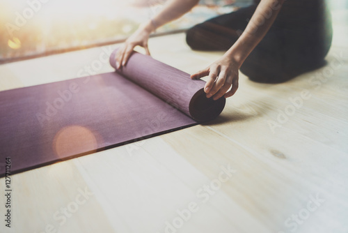 Gorgeous young woman practicing yoga indoor. Beautiful girl preparing material for practice class.Calmness and relax, female happiness concept.Horizontal, blurred background,flares.