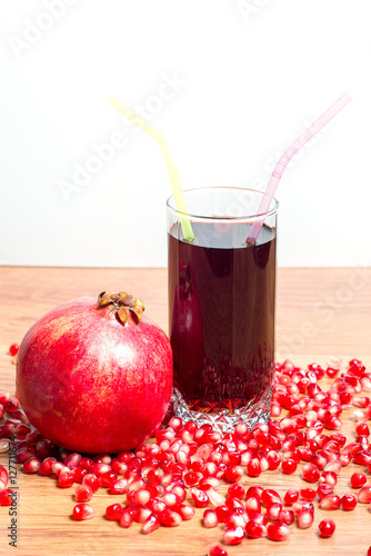 A glass of delicious pomegranate juice, pomegranate and pomegranate seeds on a table