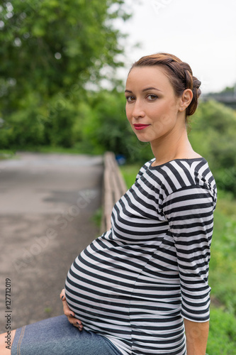 Pregnant girl sitting on a Park bench