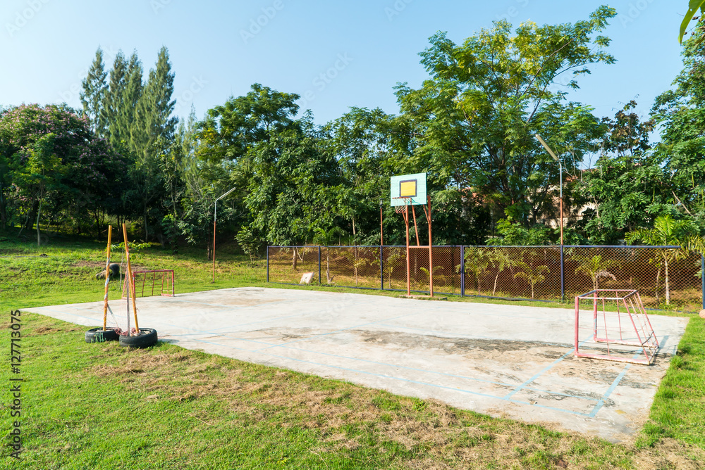 Fototapeta premium Basketball hoop in the park with green trees in background