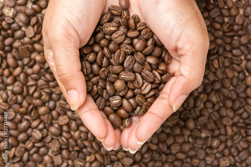 Coffee beans in hand with coffee beans background