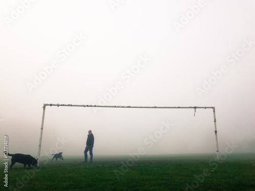 KIRKBY IN ASHFIELD, ENGLAND - OCTOBER 31: Man playing with dogs in fog at the park. In Kirkby In Ashfield, Nottinghamshire, England. On 31st October 2016. photo