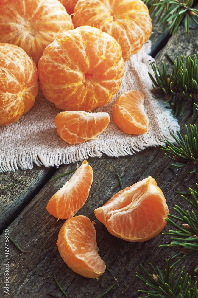 Peeled tangerines on a wooden background and fir branch Peeled tangerines on a wooden background and fir branch