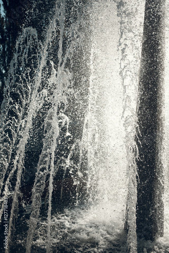 Jets of water in sunlight. Spray fountain. Splashes of water. Water drops.