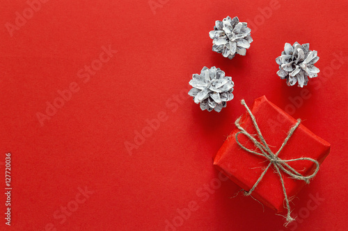 Gift box with a cones on a red background. Christmas background.