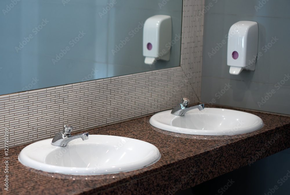 Fototapeta premium Empty public toilet room with sinks and taps.