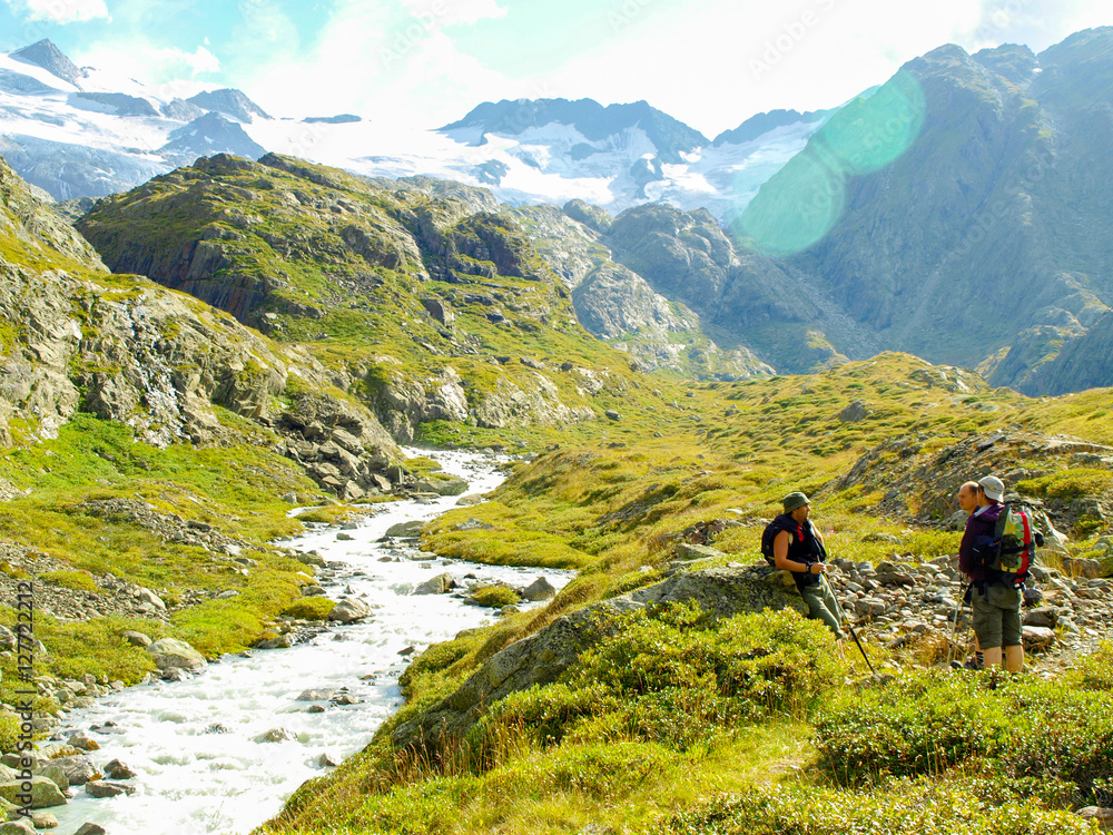 Young hikers trekking in alps, Switzerland, with mountains and astream in the background