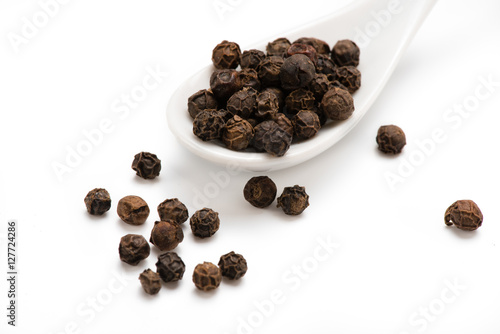 Black pepper in white spoon isolated. Spices. .