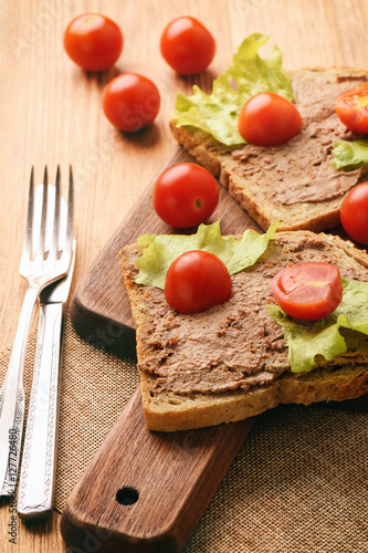 Chicken liver pate on the bread on wooden tray.