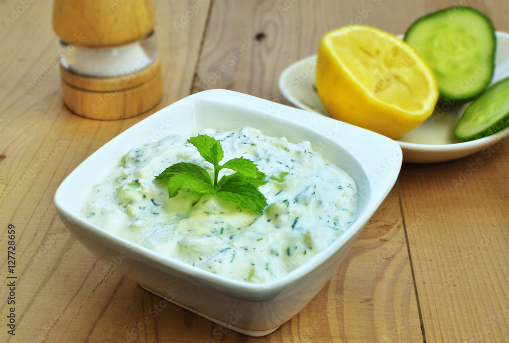 Tzatziki sauce. Greek yogurt cucumber dip in white bowl over wooden table. Tzatziki sauce. Greek yogurt cucumber dip in white bowl over wooden table.