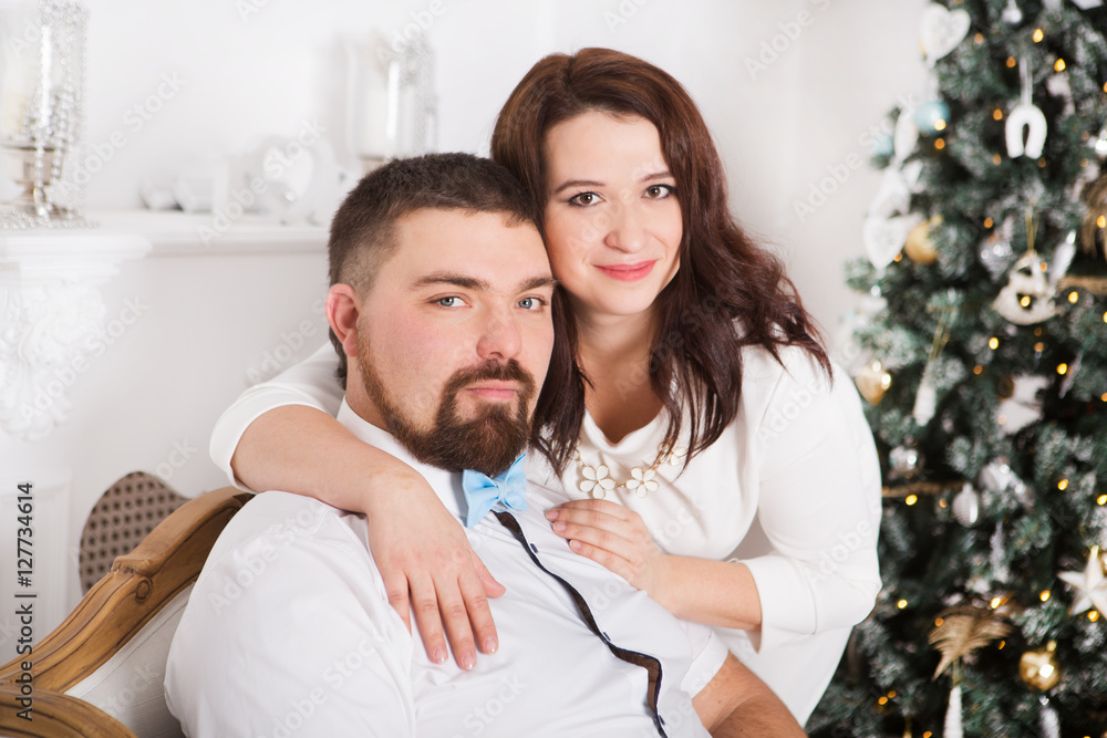 Portrait of lovely couple in christmas time sitting beside Christmas tree
Portrait of lovely couple in christmas time sitting beside Christmas tree