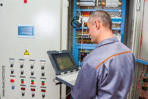 electrician testing industrial machine, electrician builder engineer screwing equipment in fuse box, Male Electrician,energy conservation, electrical work, repair of electricity power station,electric