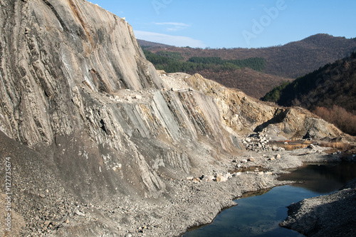 Slope of abandoned stone quarry on blue sky background in sunny day