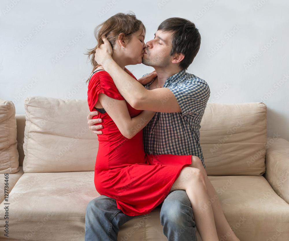 Young lovers are sitting on sofa hugging and kissing. Stock Photo | Adobe  Stock