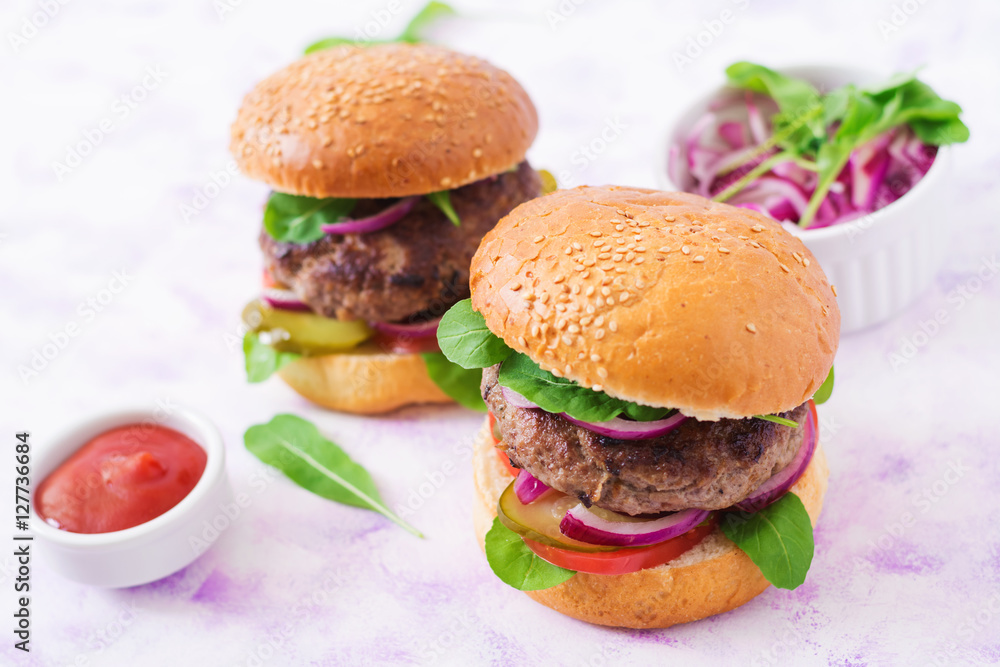 Big sandwich - hamburger burger with beef, pickles, tomato and red onions on a light background.