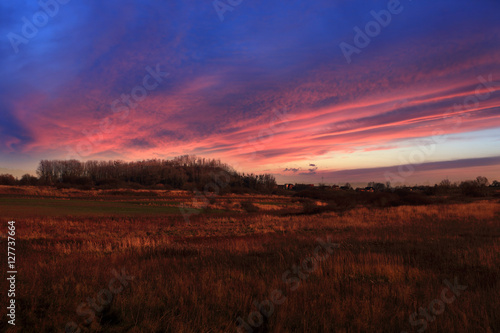 Kolorowy zachód słońca nad polami, wioską. © Stanisław Błachowicz