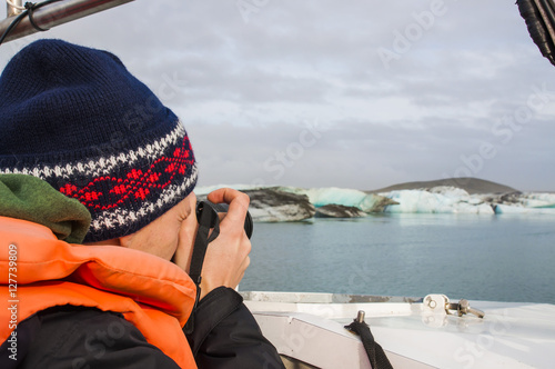 Tourist man taking a photo of ice blocks in the Jokullsarlon Iceland, also known as Glacier ice blue lagoon. photo