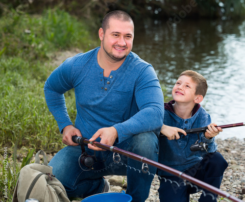 Laughing father and boy fishing with rods