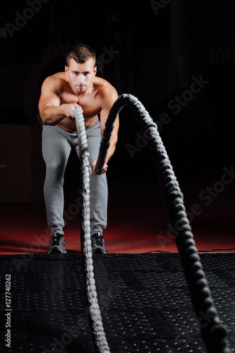 Men with battle rope in functional training fitness gym © photominus21
