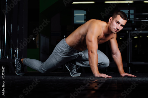young handsome man in sportswear doing push-up at gym.