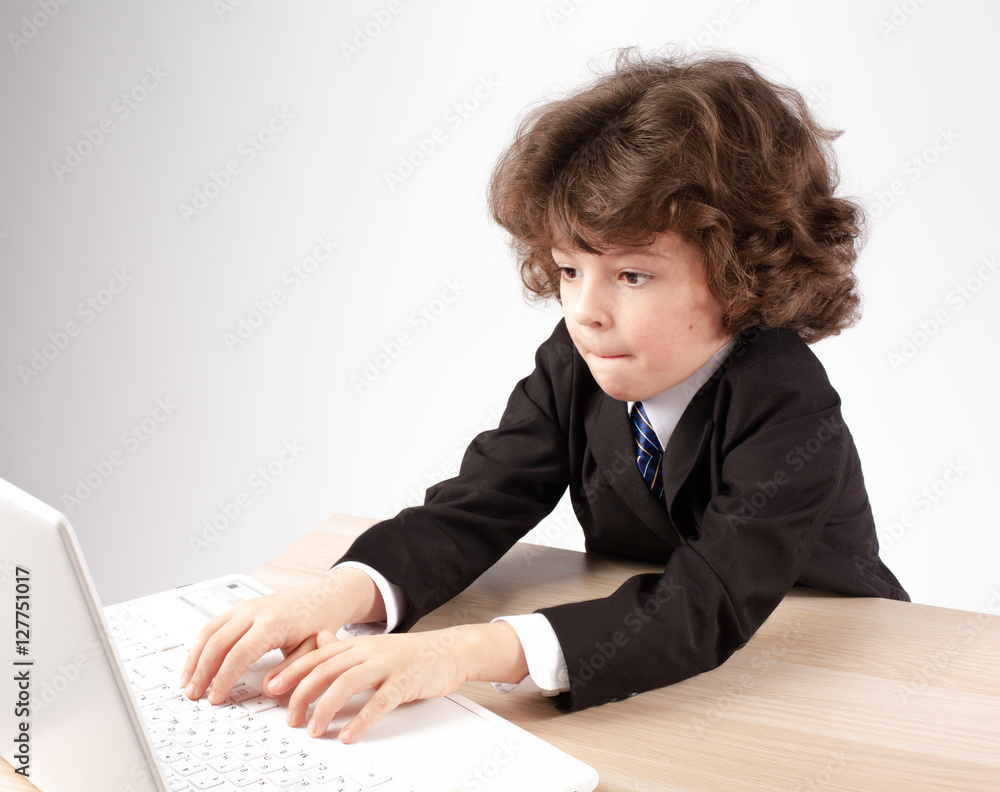 Cute little businessman typing on a laptop. Gray background. Cute little businessman typing on a laptop. Gray background.