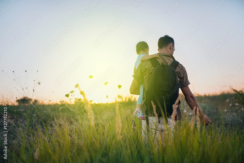 Handsome young father on his hands with his cute toddler daughter outdoor. Dad playing with his child at nature. Happy family spending time together outside at meadow and on sunset. Handsome young father on his hands with his cute toddler daughter outdoor. Dad playing with his child at nature. Happy family spending time together outside at meadow and on sunset.