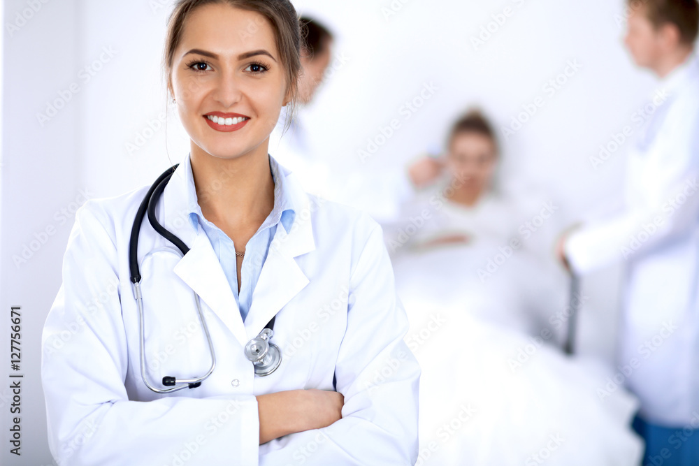 Female doctor smiling on the background with patient in the bed Female doctor smiling on the background with patient in the bed