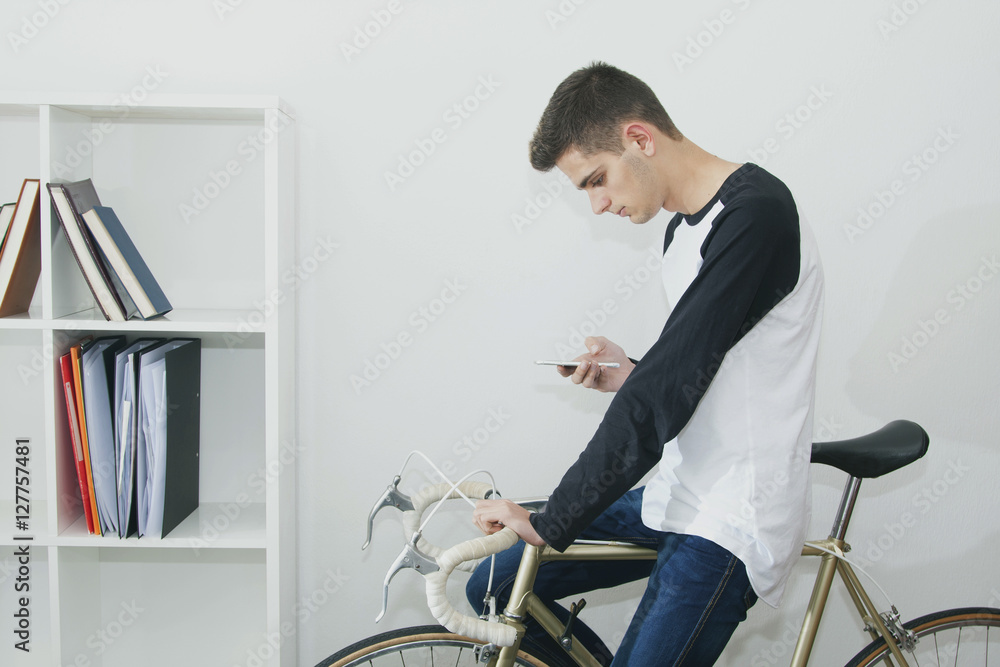 young woman with mobile phone in the house with the bike and the shelf wall young woman with mobile phone in the house with the bike and the shelf wall