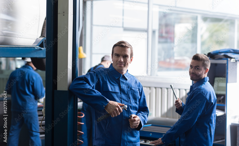 Obraz premium Cheerful auto mechanics holding tools